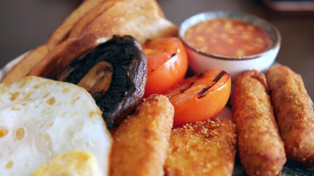 A traditional English breakfast served with baked beans, toast, fried egg, grilled tomatoes, hash browns, and mushroom arranged on a plate in Padstow, UK