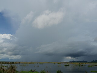 Gray Cumulonimbus cloud formations on sky above mountain, Nimbus moving in wetlands, Appearance of rain cloud, Lake while rain falling in Thailand