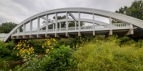 A wide, low-angle landscape view of the historic Rainbow Curve Marsh Arch Bridge (Brush Creek...