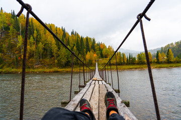 First-person point of view of a person sitting on a wooden suspension bridge looking toward the...