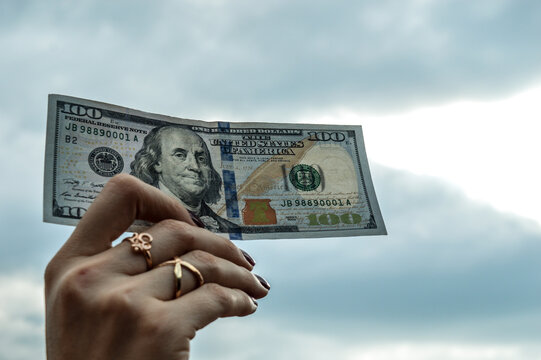 mano de mujer sosteniendo un billete de cien dolares