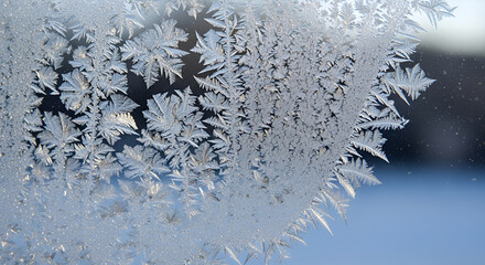 Detailed macro view of delicate frost patterns and intricate ice crystals forming on a cold glass window pane during a winter morning