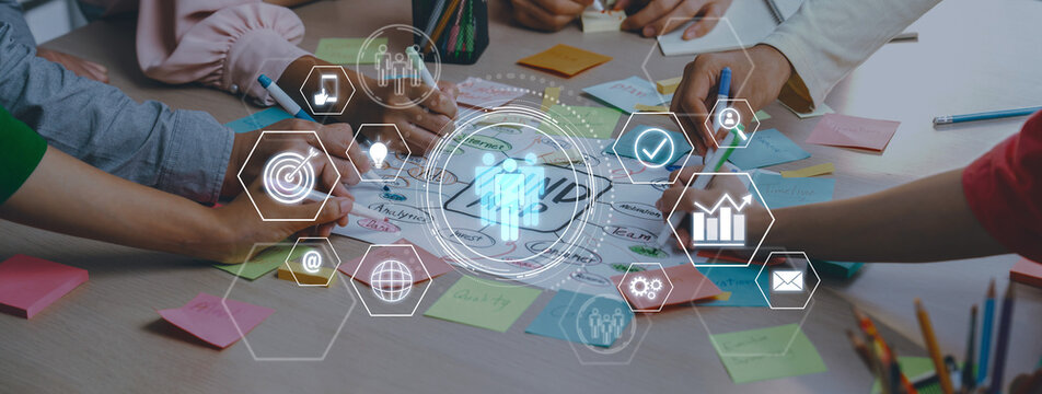 A dynamic workplace scene shows diverse hands engaged in a collaborative brainstorming session. Colorful sticky notes and digital icons enhance the creative atmosphere. Trope