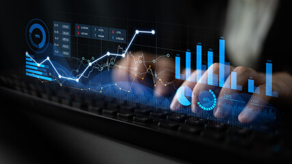 Close-up of hands on keyboard with digital graphs and charts overlay, illustrating data analysis and visualization in a modern business environment. Scalp