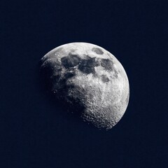 Obraz premium A close up, textured view of the moon's surface shows craters and details against a deep blue, star filled night sky.
