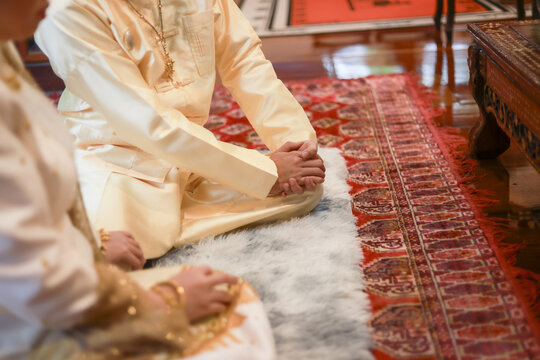 Serene South Asian couple kneeling during traditional wedding ceremony. groom and bride wear elegant attire on decorative rug, expressing respect and culture in peaceful moment - Powered by Adobe
