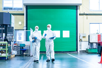 工場を歩く防護服を着た男女作業員