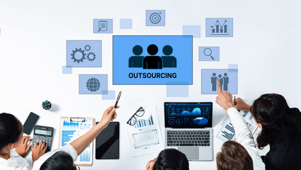 A diverse team collaborates on outsourcing strategies using charts and technology. Modern office environment fosters innovation and efficiency in business growth. Trope