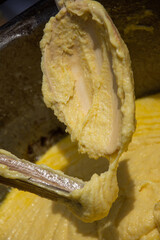 a person stirring a large batch of mămăligă, a traditional Romanian dish made from yellow maize flour. ,balmos