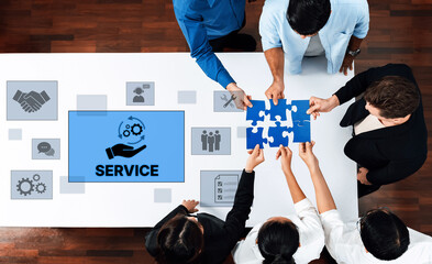 A diverse business team collaborates to solve a puzzle symbolizing service improvement, surrounded by digital icons and screens in a modern office environment. Trope