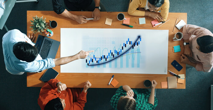 A diverse team collaborates in a business meeting, analyzing growth charts and developing strategies while engaging in creative discussions and data-driven insights. Axiom