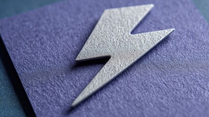 Obraz premium A close up, macro shot of a metallic silver lightning bolt symbol placed on a deep purple, textured surface with subtle glitter scattered across it.