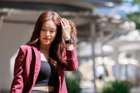 Young asian woman touching hair with smartwatch