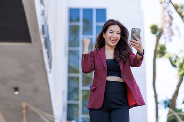 Fototapeta premium Excited woman celebrating success looking at phone