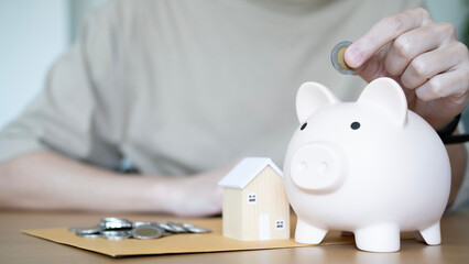 Saving coins into a piggy bank for a future home, symbolizing disciplined saving and preparation...