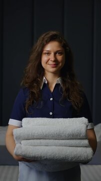 A Smiling Housekeeper Holds Fresh Towels with Confidence as She Prepares the Room for Guests, Showcasing Professionalism and Care in Hospitality Service
