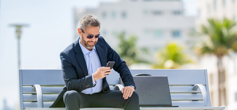 Hispanic business man with phone. Business communication. Casual business man chatting on phone outdoor. Businessman using phone. Man relax on bench with phone. Business call outdoors