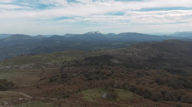 Stunning aerial view flying towards Anboto mountain, Spain. Wide drone shot with blue skies and beautiful clouds