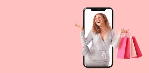 Happy woman with shopping bags on screen of mobile phone on pink background with space fore text