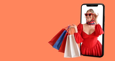 Happy woman with shopping bags on screen of mobile phone on orange background with space fore text
