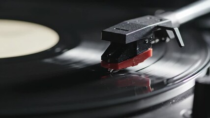 Macro view of a record player stylus tracking the grooves of a black vinyl LP record while spinning. - Powered by Adobe