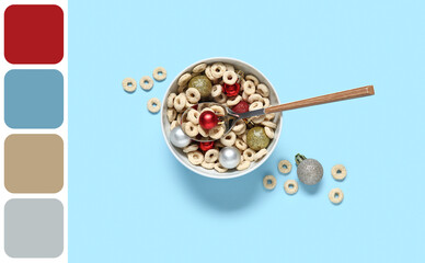Bowl of tasty cereal rings with Christmas balls on color background
