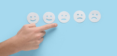 Man pointing at rating smiles on blue background. Survey concept