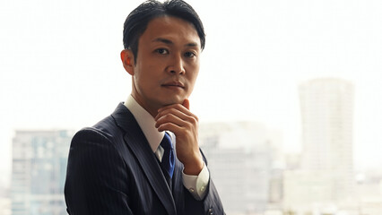 都市のオフィスビルで考えるビジネスマン