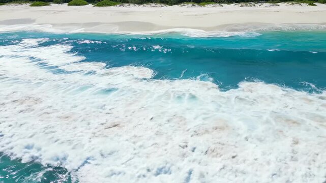 Stunning aerial drone footage capturing powerful ocean waves crashing onto a pristine, white sand tropical beach with clear blue water blue, tide, energy