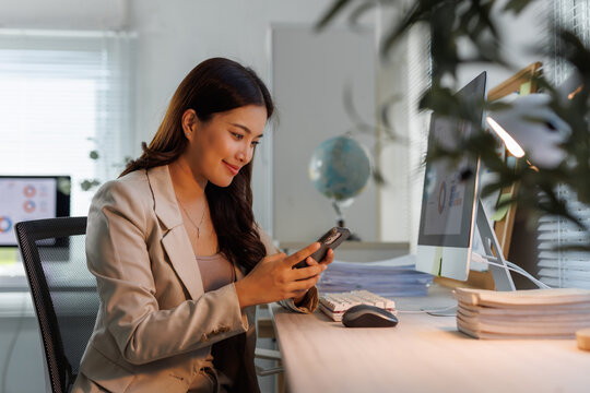 Young businesswoman communicating using smartphone in office at night