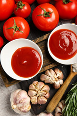 Bowls with tasty ketchup and fresh vegetables on table, closeup