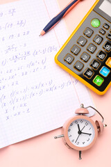 Naklejka premium Copybook with maths formulas, pen, calculator and alarm clock on pink background