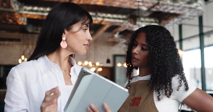 Manager, cafe and team with tablet for discussion, inventory or training. Waitress, women and technology in small business for menu planning, hospitality and coaching with owner for stock order