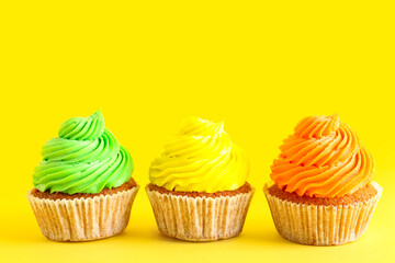 Tasty colorful cupcakes on yellow background