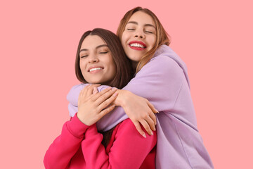 Female friends hugging on pink background