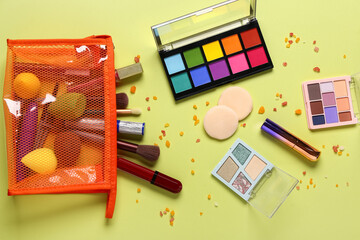 Stylish red cosmetic bag with makeup products on yellow background