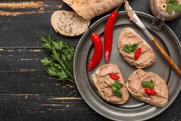 Plate with toasts, tasty pate, chilli peppers, parsley and knife on dark wooden background