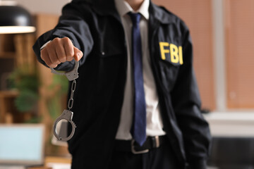Male FBI agent with handcuffs in office, closeup