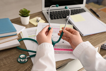 Female medical student with stethoscope at table in clinic, closeup