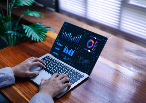 A person works on a laptop with a dashboard for data analysis and database-connected metrics for operations in finance, sales, marketing, digital transformation, and business intelligence.  