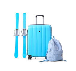 Suitcase, skis and backpack on white background