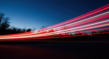 Long exposure captures bright red and white car light trails against a dark blue twilight sky