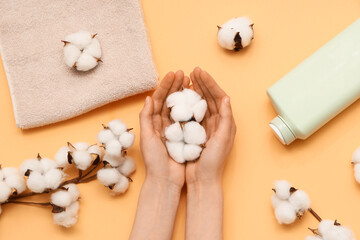 Female hands with cotton flowers on yellow background, closeup