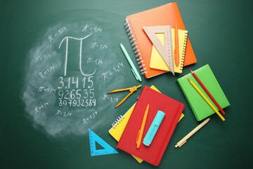 Number Pi written on green chalkboard with notebooks and stationery, top view