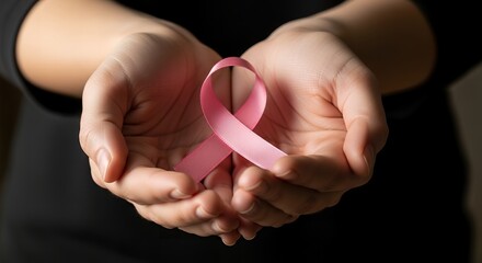 Close-up of cupped hands gently holding a delicate pink ribbon, a universal symbol for breast cancer awareness, support, and hope.