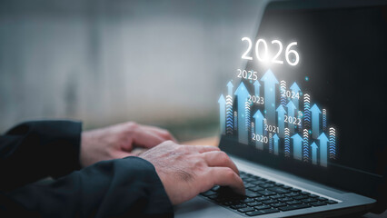 Businessman drawing digital growth arrows and bar graph with 2026 target. Futuristic concept for business goals, technology strategy, data-driven planning, success and innovation.