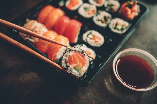 Sushi takeout featuring assorted rolls with chopsticks and dipping sauce for a delightful culinary experience