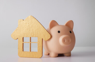 Piggy bank with golden house model on white background. Buying home, renting, mortgage concept