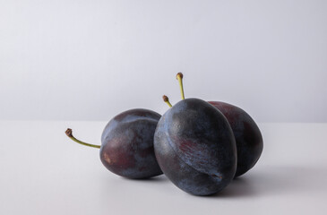 Three ripe plums on a white background