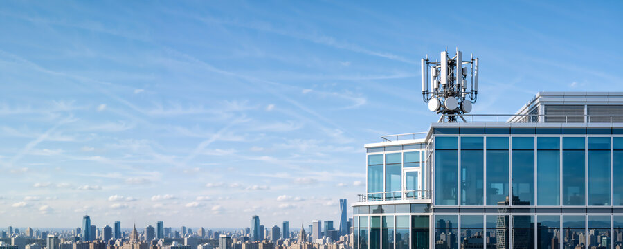 Telecommunications tower with 5G and 6G antennas on a modern building roof. Urban city skyline background with blue sky. Wireless network technology concept with copy space